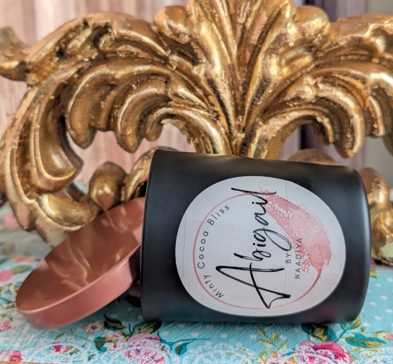 Candle with a decorative label on a floral fabric background